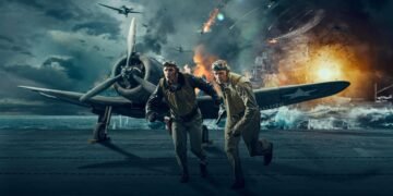 Two WWII-era airmen sprint across a carrier deck as explosions and burning ships fill the background behind them.